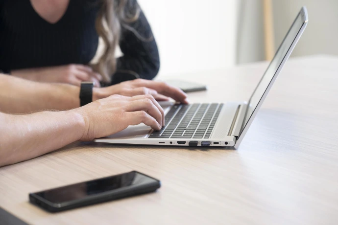 twee collega's aan de laptop met smartphone